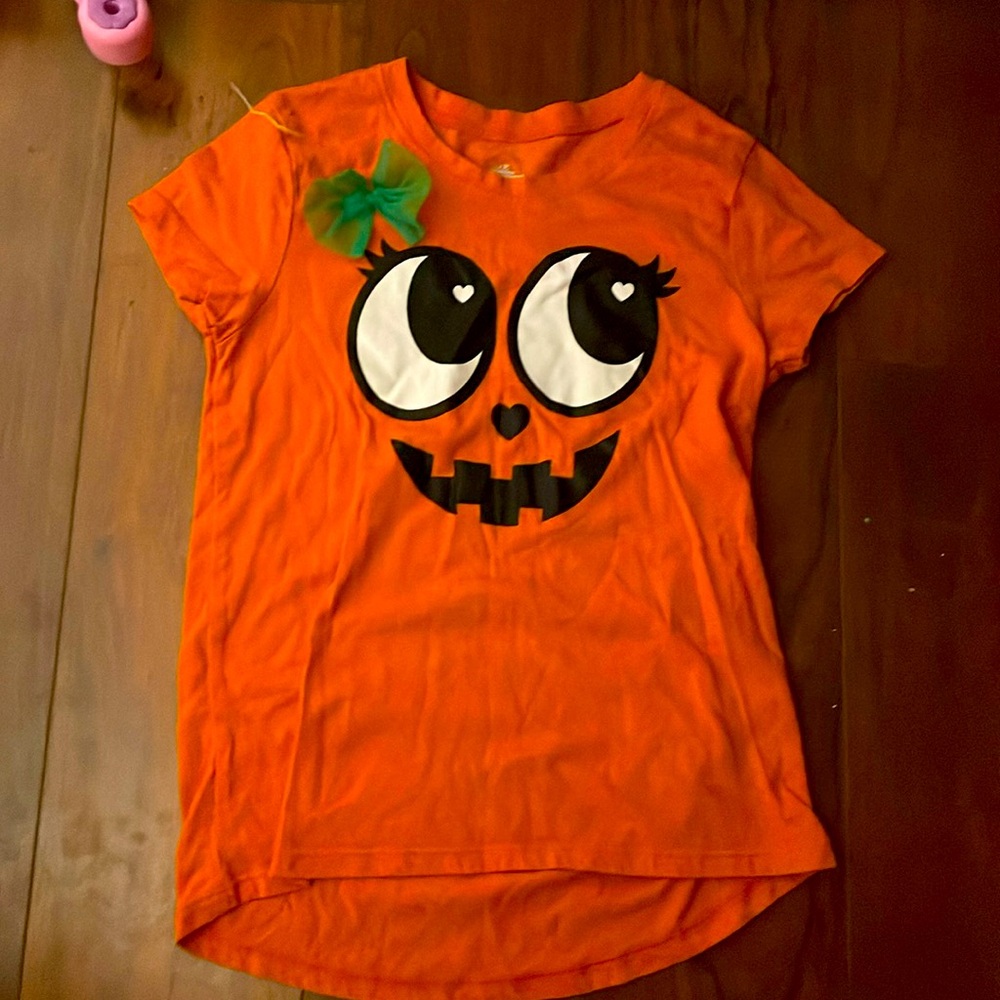 A Halloween shirt, a cute green bow, short sleeves, shorter in the back.